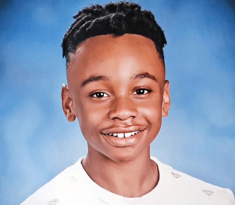 School photo of Darrel 'DJ' McCutcheon, Jr., a young student with a bright smile. He has short, dark hair and is wearing a white shirt. 