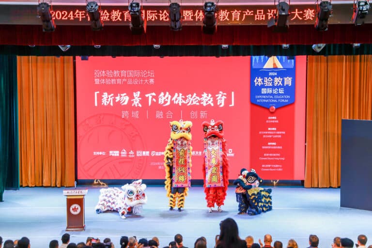 People performing a dragon dance on stage. The performers are wearing large, colorful dragon costumes, which twists and moves in flowing motions. The dragon is decorated with vibrant colors like red, gold, and white, with intricate patterns along its body.