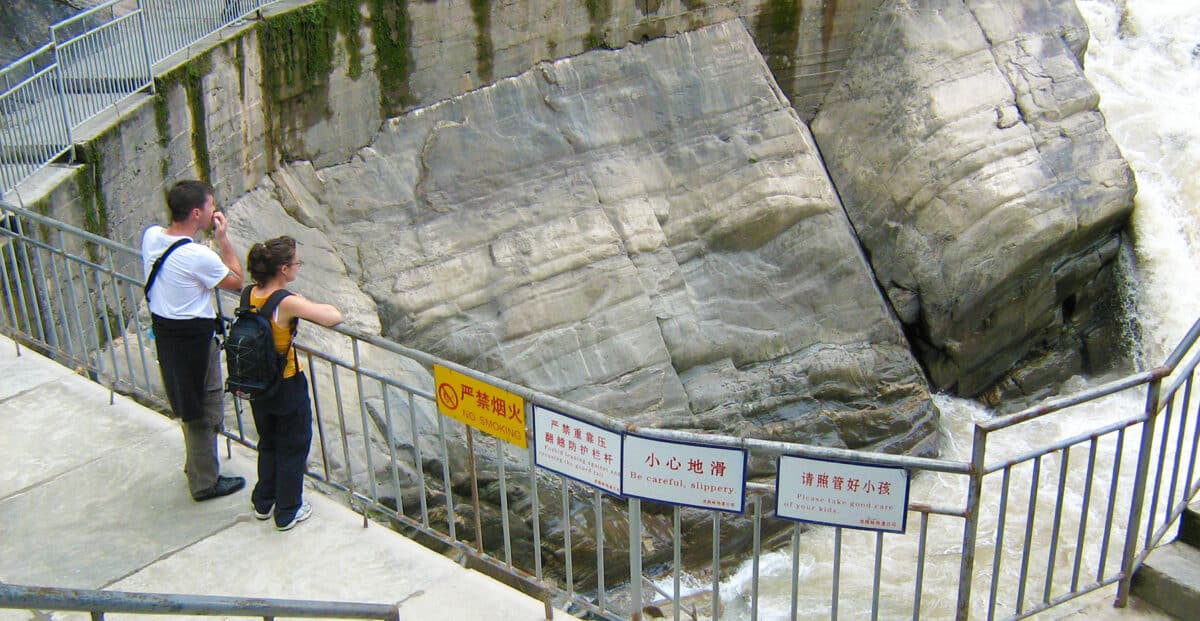 Two outdoor recreationalists stand, gazing out over the landscape of Tiger Leaping Gorge. 